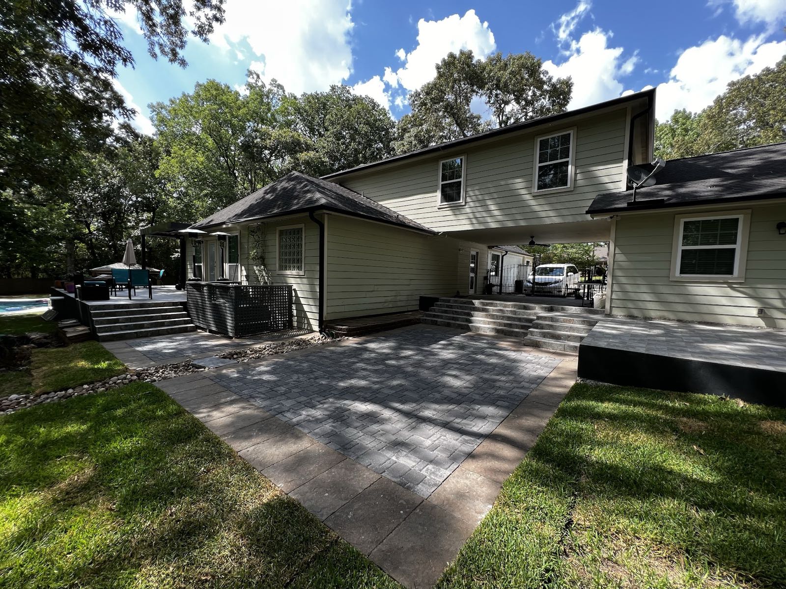 Large paver patio and walkway leading to the back of a two-story home