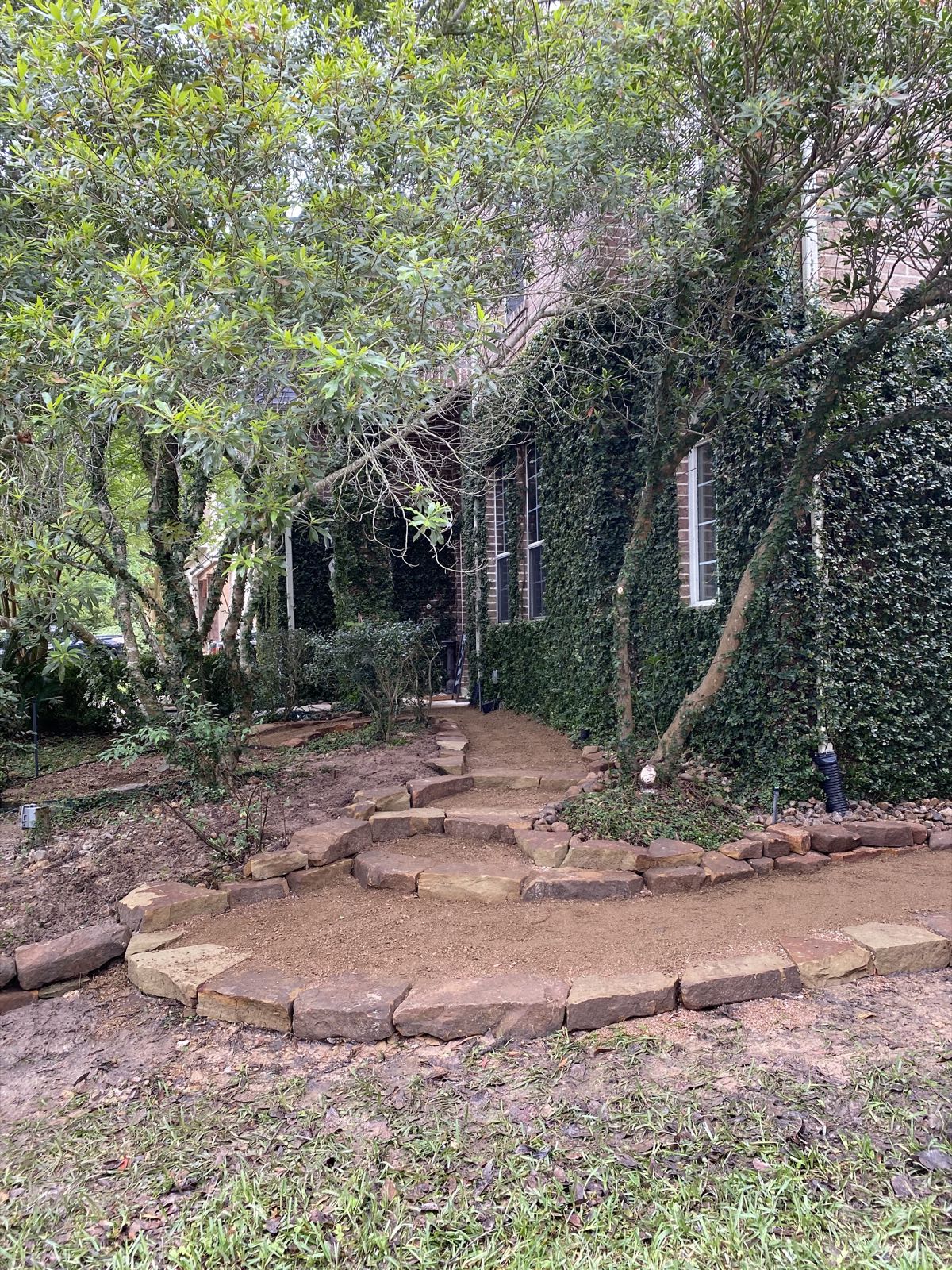 Curved stone-edged path along an ivy-covered brick house