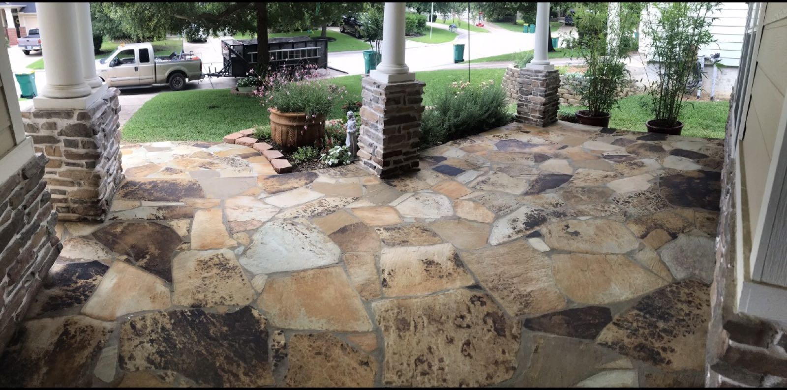 Natural flagstone front porch between stacked stone columns